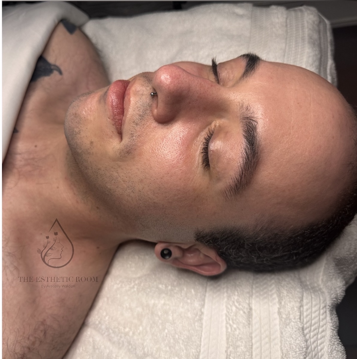 A male client laying on a bed with his eyes closed to show his skin after a facial.